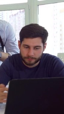 Doğal ışıkla dolu canlı bir ofiste genç erkek mimarlardan oluşan dinamik bir ekip projeleri için yenilikçi çözümler üretiyor. Gösterişli siyah kazaklı esmer sakallı mühendis tartışmayı yönetirken,