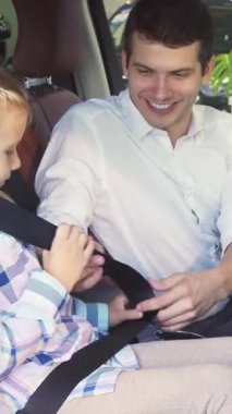 Sıcak bir arabanın içinde, kendini adamış bir baba küçük kızına emniyet kemeri takar, onun güvenliğini ve rahatlığını sağlar. Sıcak gülümsemeleri ve neşeli etkileşimleri sevgi ve güven saçıyor, neşe dolu ve sevgi dolu bir aile anını yakalıyor.