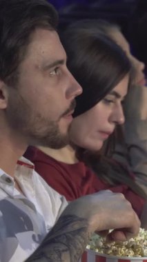 Canlı dört arkadaştan oluşan bir grup, renkli bir sinema salonunda, tamamen filme dalmış neşeli bir film gecesini paylaşıyor. Koyu renk saçlı genç adam patlamış mısırın tadını çıkarırken, uzun dalgalı saçlı kız arkadaşı telefonuna ışık saçıyor ve bir atmosfer yaratıyor.