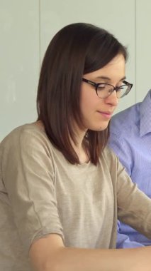 Parlak ve şık bir ofiste, odaklanmış, gözlüklü beyaz bir kız parlak bir işaret, somut bir yaratıcılık ve işbirliği kullanarak kağıda tutkuyla resim çiziyor. Yakışıklı, esmer bir adam da dahil olmak üzere nişanlı iş arkadaşlarıyla çevrili.