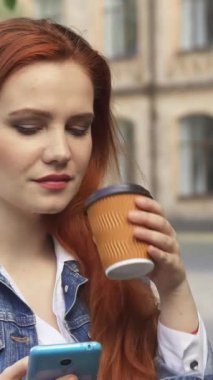 Uçan kızıl saçlı neşeli beyaz bir kız öğrenci akıllı telefonuyla mesajlaşırken moda bir bardaktan kahvesinin tadını çıkarıyor. Çekici bir kampüs arkaplanına, ışıl ışıl gülüşüne ve gevşek tavırlarına rağmen öğrencinin coşkulu ruhunu somutlaştırıyor.