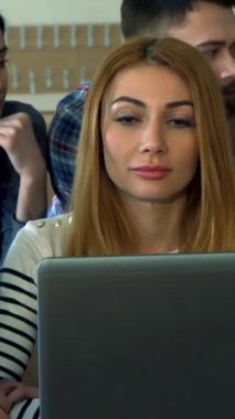 Aralarında gülümseyen esmer bir kadın ve odaklanmış sakallı bir adamın da yer aldığı coşkulu ve çeşitli öğrencilerden oluşan bir grup, parlak bir dizüstü bilgisayarın etrafında toplanarak fikir alışverişinde bulunuyor. Canlı kolej salonu enerji ile uğulduyor.