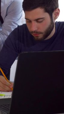 Üç Kafkasyalı mimar, canlı planlar ve proje belgeleriyle çevrili şık bir çalışma masasında tutkuyla işbirliği yapıyor. Donanma tişörtlü, odaklanmış esmer sakallı bir adam özenle fikir çizer, takım çalışmasının ruhunu somutlaştırır.