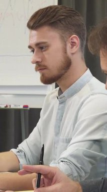 Şık sakallı neşeli bir genç, olgun meslektaşına ışıldıyor. Modern bir ofiste parlak bir dizüstü bilgisayarla parlak fikirler üretiyorlar. Bu canlı sahne, takım çalışmasının özünü güzel bir şekilde yakalıyor.