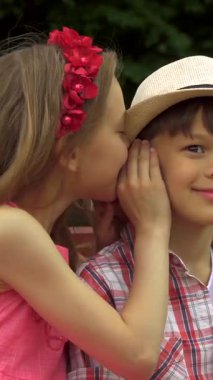 Işıl ışıl bir yaz gününde, sevimli küçük bir kız sırlarını paylaşmak için sırlarını hem neşe hem de masumiyet saçan bir çocukla paylaşır. Renkli kıyafetleri ve şakacı ifadeleri dostluğun iç açıcı bir sahnesini oluşturuyor.