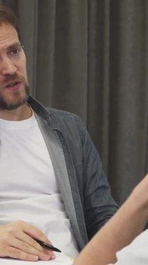 Olgun, sakallı bir iş adamı genç meslektaşı ile zarif gri perdelerle süslenmiş modern bir toplantı odasında ateşli bir şekilde tartışır. Yenilikçi alışverişler sırasında atmosfer yaratıcılık ve işbirliğiyle uğulduyor.