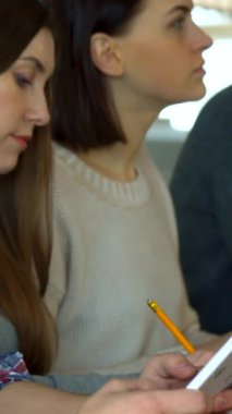 Sakallı bir erkek öğrenci yüzünü kameraya doğru çevirir, canlı ve kareli bir tişörte güvenerek, odaklanmış bayan sınıf arkadaşları canlı bir konferans salonunda meşgul olurlar. Bu büyüleyici sahne modern eğitimin dinamik atmosferini gözler önüne seriyor