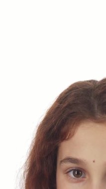 Yakın plan, zarif bir kurdeleyle güzelce sarılmış parıldayan bir hediyeyi hevesle kaldırırken şaşaalı gözlerle parlayan bir kızı gözler önüne seriyor. Saf beyaz arka plan onun neşeli yüz ifadesini güçlendirir, büyüleyici ruhunu yakalar.