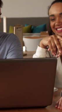 Şık bir dekorla dolu canlı bir kafede esmer sakallı bir adam, Afrikalı bir Amerikalı kadın ve beyaz bir sarışın dizüstü bilgisayarla uğraşırken neşeli bir şekilde gülümsüyor. Yumuşak ışıklandırma ve davetkar renkler ile tamamlanan ılık ortam,