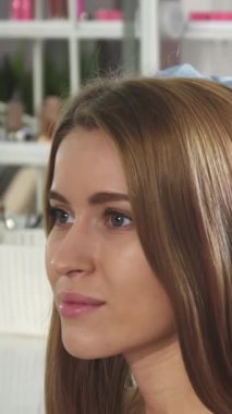 Bu yakın planda, yetenekli bir kadın kuaför muhteşem genç müşterisinin saçlarını kıvırarak saç stilini ve sanatını ön plana çıkarıyor. Modern aletler ve yumuşak, davetkar aydınlatmalarla süslenmiş şık salon, canlı bir ışık yaratıyor.