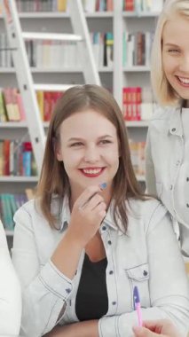 Neşeli üniversite öğrencilerinden oluşan canlı bir grup üniversite kütüphanesinde, enerjik ve davetkar bir atmosfer yaratarak kahkaha ve fikirleri paylaşıyor. Neşeli ifadeleri, hareketli tartışmaları ve renkli çevreleri,