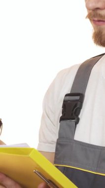 Gri üniformalı gülümseyen sakallı bir adam çalışkan sarı bir panoya yazarak inşaat endüstrisine profesyonellik ve coşku saçıyor. Sıcak ifadesi ve odaklanmış duruşu, kalite ve uzmanlığa olan bağlılığını vurguluyor.