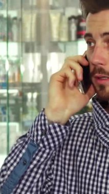 Düşünceli bir esmer adam elinde renkli haplar şişesini dikkatle incelerken bir telefon görüşmesi yapıyor. Sağlıklı ürünlerle dolup taşan canlı raflarla çevrelenmiş, bilgilendirilmiş karar verme mekanizmasının özünü somutlaştırıyor.