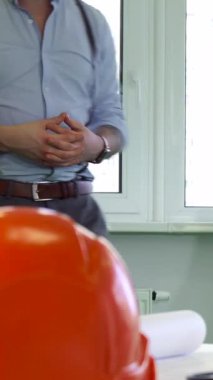 Bu canlı sahnede, iki erkek mimar, karmaşık bir masada, planlar ve aletlerle dolu bir masada tutkulu bir şekilde tartışırlar. Sıcak doğal ışık boşluğu sarıyor. Beyin fırtınası yaparken odaklanmış ifadelerini aydınlatıyor.