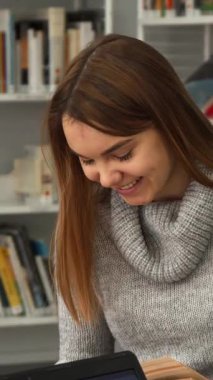 Neşeli, kahverengi saçlı, rahat gri kazaklı bir kız heyecanlı bir şekilde heyecanlı bir kitaptaki düşünceli sınıf arkadaşıyla canlı bir kütüphanede ilginç sezgilerini paylaşıyor. Etrafı renkli iki beyaz öğrenci arasındaki bu canlı değişim...