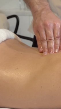 Yetenekli bir erkek terapistin rahatlatıcı bir sırt masajını rahatlatıcı bir spa atmosferiyle sarmaladığı sakin bir sahne sergiliyor. Pürüzsüz cildindeki parlak yağ yumuşak, çevresel ışığı yakalar ve lüks bir atmosfer yaratır.