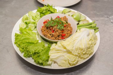 Biber daldırma uzun taze fasulye, patlıcan, marul, dilimlenmiş salatalık, beyaz turp ve Goa ile baharatlı domuz pirzolası veya kanat fasulye, Tayland popüler yemekleri buharda pişmiş pirinç ile yemek