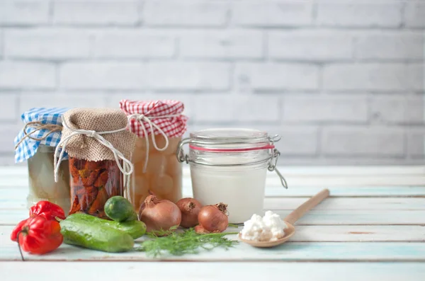 Naturally fermented foods in jars including kefir, gherkins and peppers and onions