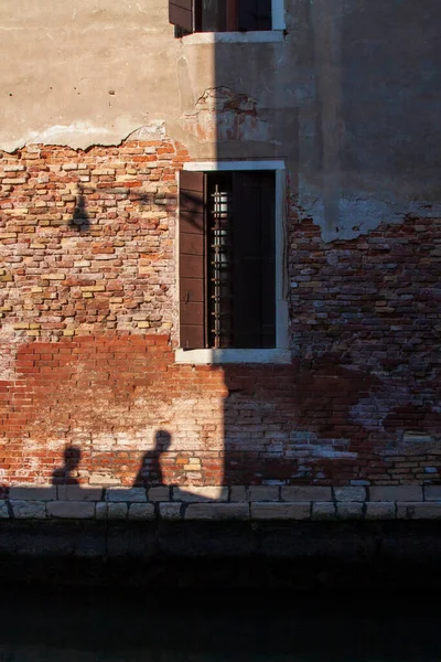 Old wall in evening light. Silhouettes of people