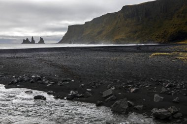 Siyah kum ve Reynisdrangar, Bazalt deniz yığınları üzerinde İzlanda'nın Güney kıyılarında Vik balıkçı köyü yakınındaki bir görünüm.