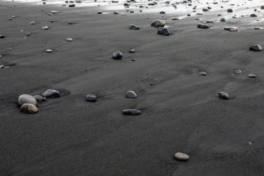 İzlanda'nın Güney sahil üzerinde Vik balıkçı köyü yakınındaki Reynisfjara plajda, siyah kum ve çakıl bir görünüm.