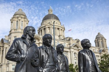 Liverpool, İngiltere - 30th Temmuz 2018: Liverpool, İngiltere'de tarihi şehir içinde arka planda Bina Beatles - Paul Mccartney, George Harrison, Ringo Starr ve John Lennon - Liverpool bağlantı noktası ile heykelleri. 
