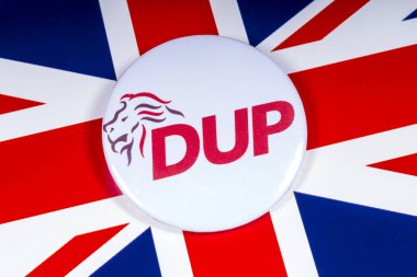 London, UK - November 15th 2018: A Democratic Unionist Party pin badge, pictured over the UK flag. clipart
