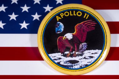 London, UK - November 15th 2018: The badge of the historic Apollo 11 moon landing, pictured over the flag of the United States of America. clipart