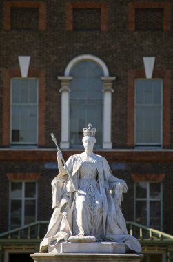 Londra, İngiltere - 27th Eylül 2018: Kensington Gardens Londra'da Kraliçe Victoria taç giyme elbisesi 1837 yılında tasvir eden bir heykel. Kensington Sarayı'nın dış arka planda olduğunu. 