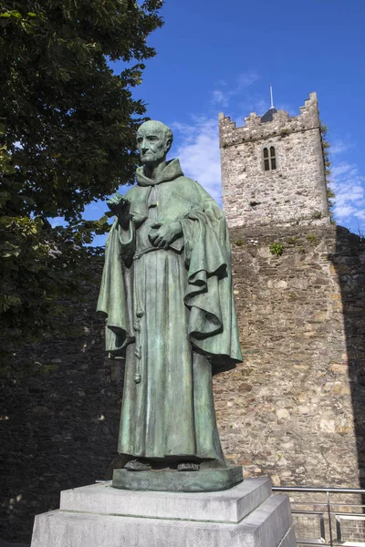 A statue of Irish Franciscan friar Luke Wadding with the French Church friary in the background, in the historic city of Waterford in Republic of Ireland.