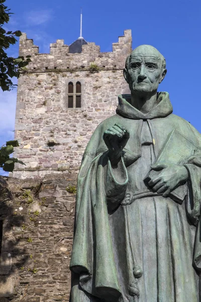 A statue of Irish Franciscan friar Luke Wadding with the French Church friary in the background, in the historic city of Waterford in Republic of Ireland.