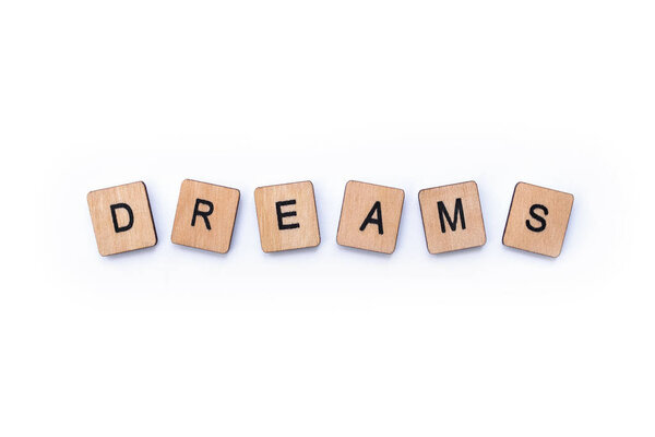 The word DREAMS, spelt with wooden letter tiles, over a white background.