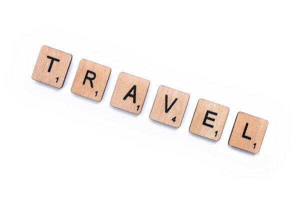 London, UK - February 13th 2019: The word TRAVEL, spelt with wooden letter tiles, over a white background.