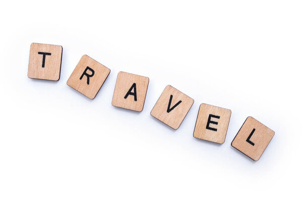 The word TRAVEL, spelt with wooden letter tiles, over a white background.