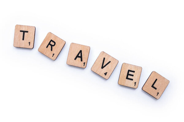 London, UK - February 13th 2019: The word TRAVEL, spelt with wooden letter tiles, over a white background.