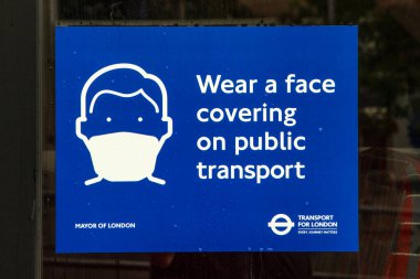 Londra, İngiltere - 17 Haziran 2020: Londra, İngiltere 'deki bir otobüsün dış tarafında Face Covering tabelası. Hükümet, toplu taşıma araçlarını kullanırken yüz maskelerinin artık zorunlu olduğunu açıkladı..