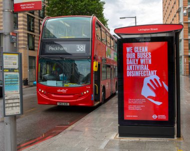 Londra, İngiltere - 17 Haziran 2020: Coronavirus salgını sırasında bir otobüs durağında, otobüslerin antiviral dezenfektanla temizlendiğine dair banliyö banliyölerini bilgilendiren bir pano gösteren bir pano.