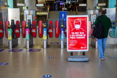 Londra, İngiltere - 24 Haziran 2020: Londra 'daki bir tren istasyonunda bir bilgi levhası, Coronavirus salgını sırasında toplu taşıma sırasında yolculardan yüz maskesi takmalarını veya yüz maskesi takmalarını istiyor.