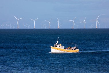 Llandudno, Galler - 3 Eylül 2020: Kuzey Galler kıyılarında Gwynt y Mor açık deniz rüzgar çiftliği ile seyahat eden bir tekne - dünyanın en büyük 5..  