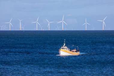 Llandudno, Galler - 3 Eylül 2020: Kuzey Galler kıyılarında Gwynt y Mor açık deniz rüzgar çiftliği ile seyahat eden bir tekne - dünyanın en büyük 5..  