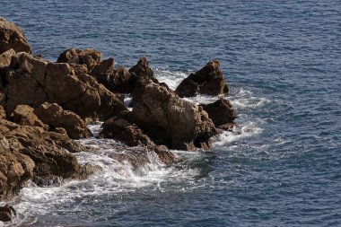 Dalgalar üzerinde sabah güneş ışınlarının kayalarda. Metniniz için bir yer. Seçici odak ile
