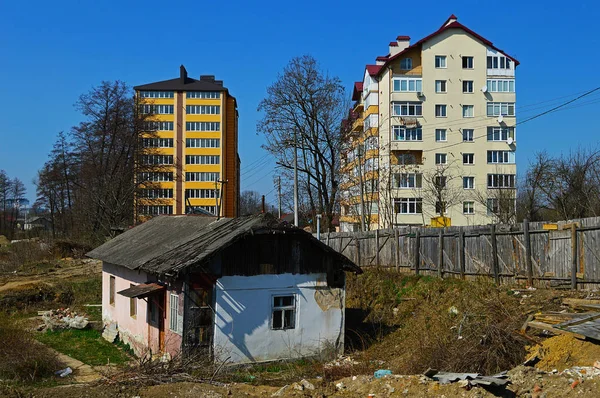 An old damaged house on the background of new buildings — Stock Photo, Image