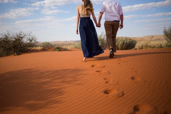 一对漂亮的情侣手拉手走在南非卡拉哈里地区的红沙丘上 — 图库照片