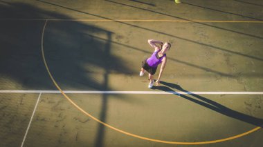 Yükü bir dron ile gelen genç bir kadın tenis kortunda tenis oynamaya havadan görüntü vurdu