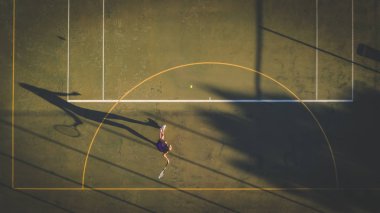 Yükü bir dron ile gelen genç bir kadın tenis kortunda tenis oynamaya havadan görüntü vurdu