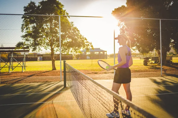 Close up portrait of a female tennis player on a tennis court with beautiful warm back light sunset.