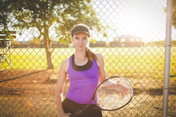 关闭在一个网球场上的女性网球运动员的肖像与美丽的温暖的背灯日落 — 图库照片