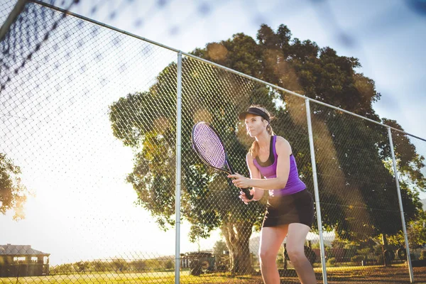 在明亮的阳光下 关闭一个女网球运动员在球场上打网球的照片 — 图库照片