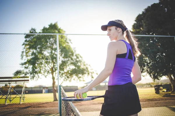 关闭在一个网球场上的女性网球运动员的肖像与美丽的温暖的背灯日落 — 图库照片
