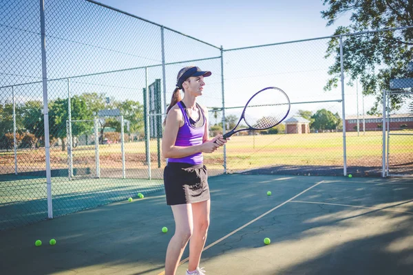 在明亮的阳光下 关闭一个女网球运动员在球场上打网球的照片 — 图库照片